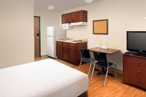 a hotel room with a bed and a table and a kitchen at WoodSpring Suites San Antonio Fort Sam in San Antonio