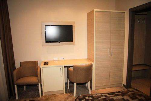 a room with a desk with two chairs and a television on the wall at Hotel Palazzo in Gornji Vakuf