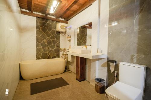 a bathroom with a tub and a toilet and a sink at The Phalosaa Villa unit Family in Ngaglik