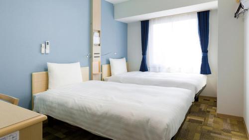 two beds in a room with blue walls and a window at Toyoko Inn Shonan Chigasaki eki Kita guchi in Chigasaki