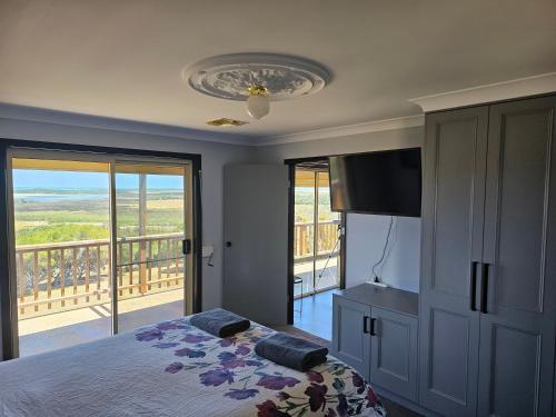 a bedroom with a bed and a television and a balcony at Magic at the Mouth in Nelson