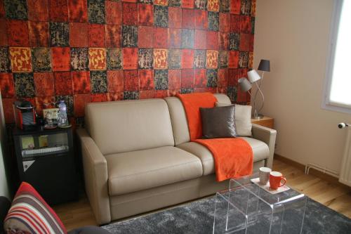 a living room with a couch and a tiled wall at Les Suites Champenoises in Reims