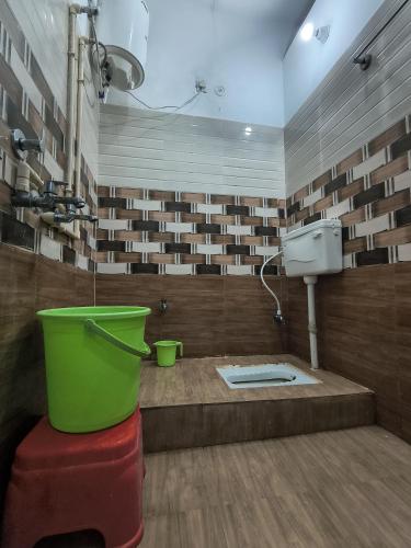 a bathroom with a toilet and a green bucket at Jai Krishna Guest House in Ayodhya