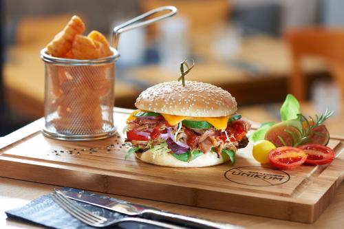 a sandwich and french fries on a wooden cutting board at Hotel Hanauerhof in Appenweier