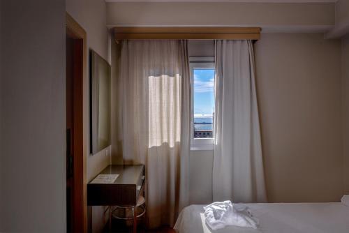 a bedroom with a window and a bed and a desk at Astoria Hotel Thessaloniki in Thessaloniki