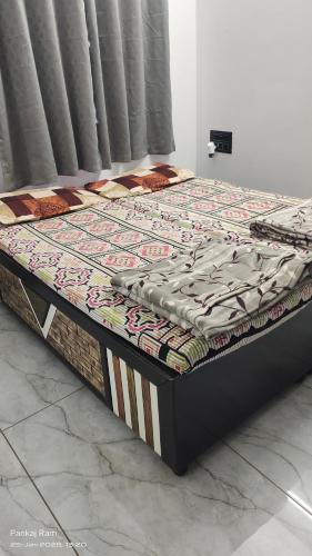 a bed sitting in a room next to a window at Shree Krushn in Bhuj