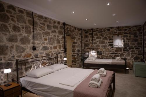 a bedroom with two beds and a stone wall at Stone Olympi Lodges - Chios Cozy Hideaways in Olýmpoi