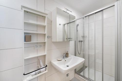 a white bathroom with a sink and a shower at Appartements Kanauf in Krumpendorf am Wörthersee
