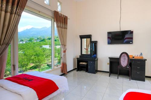 a bedroom with a bed and a large window at RedDoorz at Jestro Guest House Batu in Tlekung