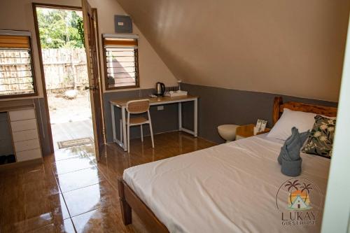 a bedroom with a bed and a table and a desk at Lukay Guest House in Siquijor in Lazi