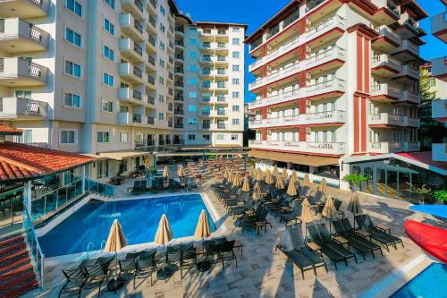 a swimming pool with chairs and umbrellas next to buildings at Villa Sunflower Hotel - All Inclusive in Alanya