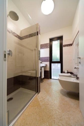 a bathroom with a shower and a tub and a sink at Villa Elysium in Torri del Benaco
