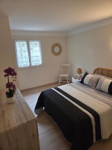 a bedroom with a bed and a table and two windows at Le chemin du bonheur in Nyons
