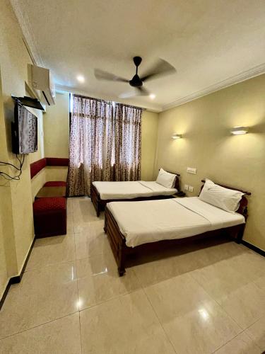 a bedroom with two beds and a ceiling fan at Mareena Regency in Cochin