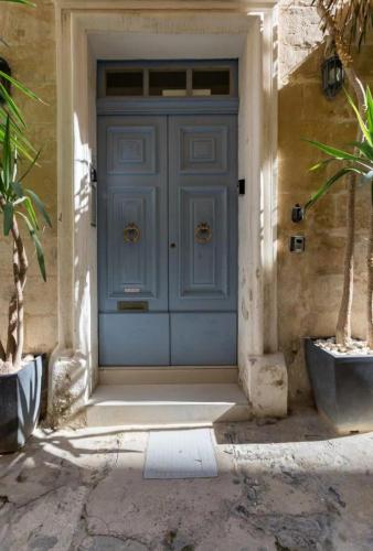 a blue door of a house with two potted plants at Charming Valletta Escape Unesco Area in Valletta