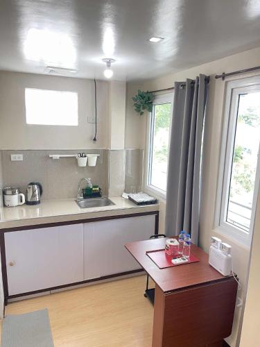 a kitchen with a sink and a table and two windows at Potot Haven Dorm and Transient in Libmanan