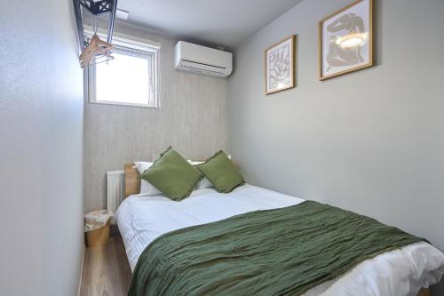 a bedroom with a bed with green sheets and a window at Niseko Town Retreat ONYX in Kutchan