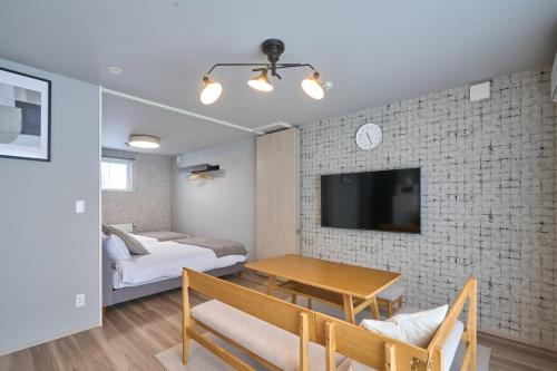a living room with a table and a tv on a brick wall at Niseko Town Retreat ONYX in Kutchan
