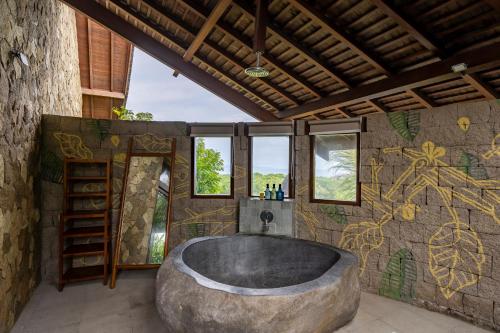 a large stone tub in a bathroom with graffiti on the wall at Khaya Luxury Villas Nusa Dua in Nusa Dua