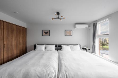 a bedroom with a large white bed with a window at Hills Niseko B in Niseko