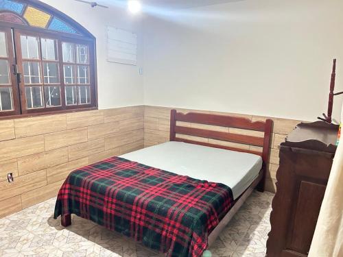 a bedroom with a bed with a plaid blanket on it at Refúgio ao mar in Rio das Ostras
