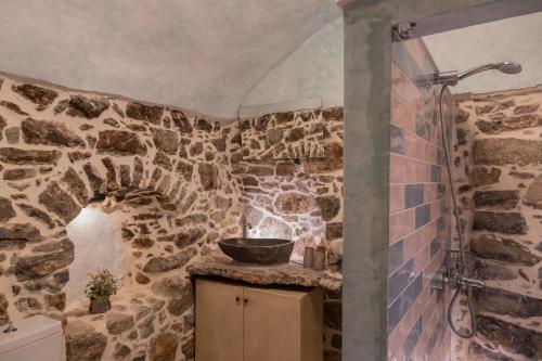 a stone bathroom with a sink and a shower at Vlychos Olympi Lodges - Chios Cozy Getaways in Olýmpoi