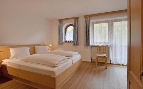 a bedroom with two beds and a chair at Gasthof Appartement`s Staffnerhof in Kössen