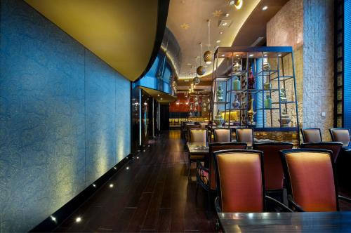 a restaurant with chairs and tables and a blue wall at Zhaolin Grand Hotel in Beijing