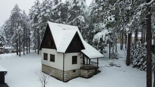 a small house with a snow covered roof in the snow at Vila Lika in Zlatibor
