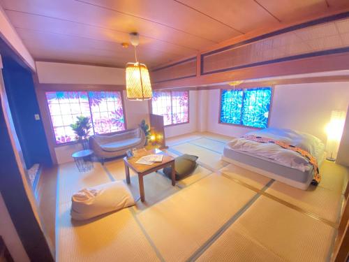 a room with a bed and a table and windows at Kaido Yuzawa Onsen Hostel in Yuzawa