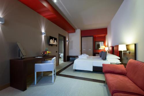パルマにあるHotel Parma & Congressiのベッドルーム1室(ベッド1台、デスク、ソファ付)