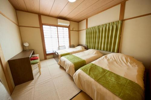 two beds in a room with a window at TSUMUGI 紡 ー Garden Villa in Nagano in Nagano
