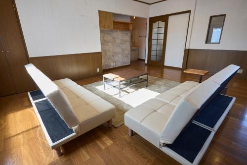 a living room with two white chairs and a table at TSUMUGI 紡 ー Garden Villa in Nagano in Nagano