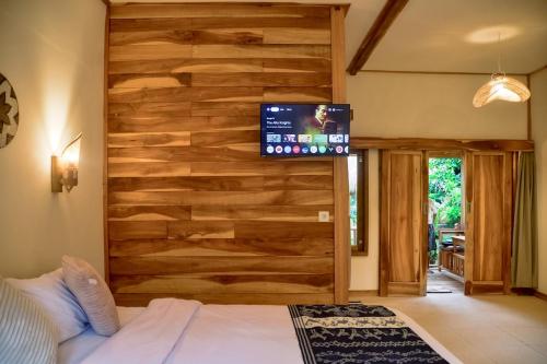 a bedroom with a wooden wall with a tv on it at Beda gaya ecolodge Rangsot 1 in Tanjung