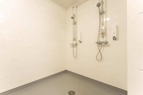 a bathroom with a shower with white tiles at LODGE Hostel Ylläs in Äkäslompolo