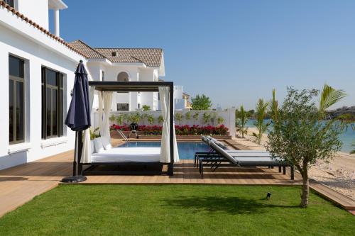 a house with a swimming pool and an umbrella at Maison Privee - Villa on Beach with Private Pool The Palm Jumeirah in Dubai