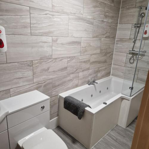 a bathroom with a tub and a toilet and a sink at The Dorchester Hotel & serviced apartments FREE PARKING in Hull