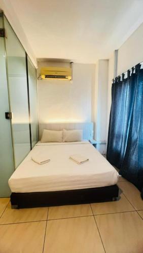 a bedroom with a white bed with blue curtains at Coastline Hotel in Port Dickson