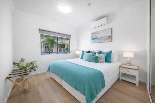 a white bedroom with a bed and a window at Waterfront Apartment Near City, Stadium & Ferry Townsville in Townsville