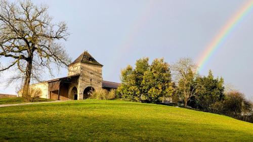 a rainbow in the sky over a building with a field at Au Clair de Vianne Ce sont les petits détails qui font la différence in Vianne