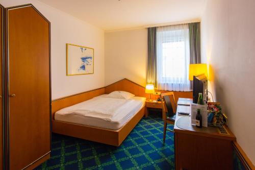 a small hotel room with a bed and a desk at Hotel Kongress in Leoben