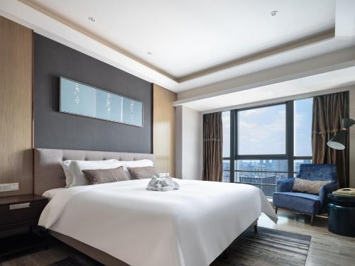 a bedroom with a large white bed and a large window at Modena by Fraser Changsha in Changsha