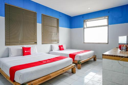 two beds in a room with blue and white walls at RedDoorz near Jawa Timur Park 1 in Batu