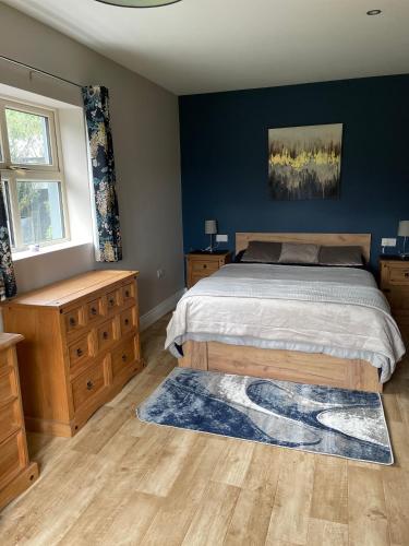 a bedroom with a bed and a blue wall at Greenway Cottage in Baltonʼs Cross Roads