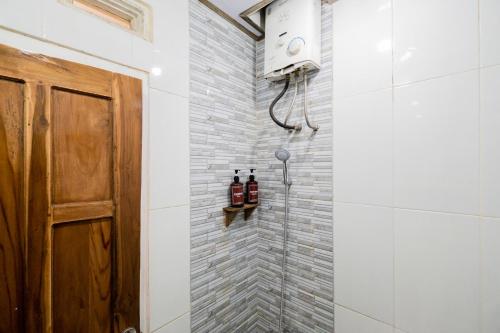 a shower stall in a bathroom with a wooden door at RedDoorz at Omahku Guest House Batu in Malang