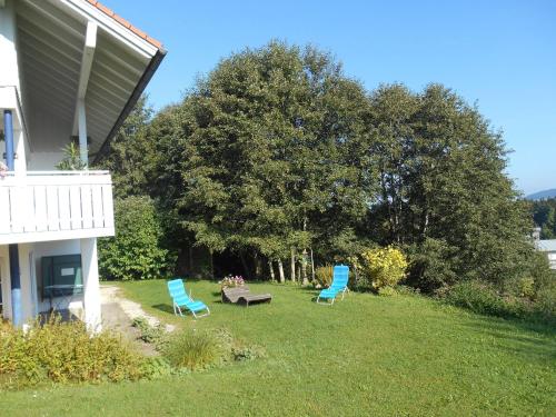 two blue chairs and a bench in the yard of a house at Ferienwohnung Rath in Oberreute