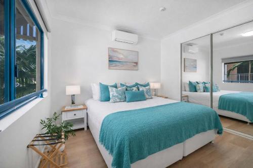 a bedroom with two beds with blue pillows at Waterfront Apartment Near City, Stadium & Ferry Townsville in Townsville