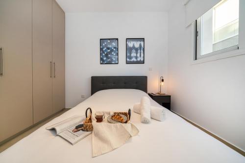 a white bedroom with a bed with two bags on it at 1 bedroom flat next to university in Aglantzia