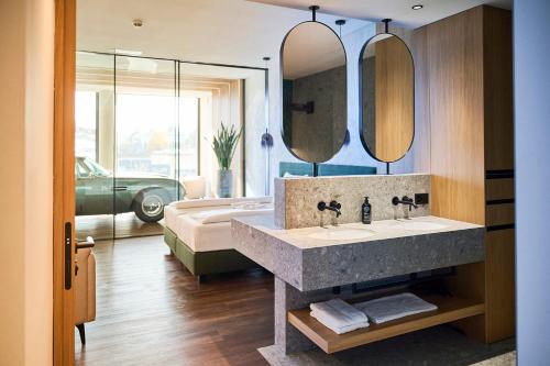 a bathroom with a sink and two mirrors and a bed at Hotel von Rotz in Wil