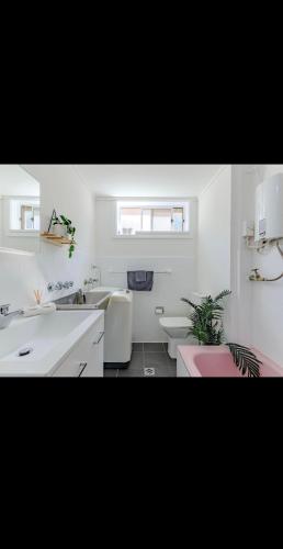 a white bathroom with two sinks and two toilets at Top Location Beachside Apartment in Cronulla